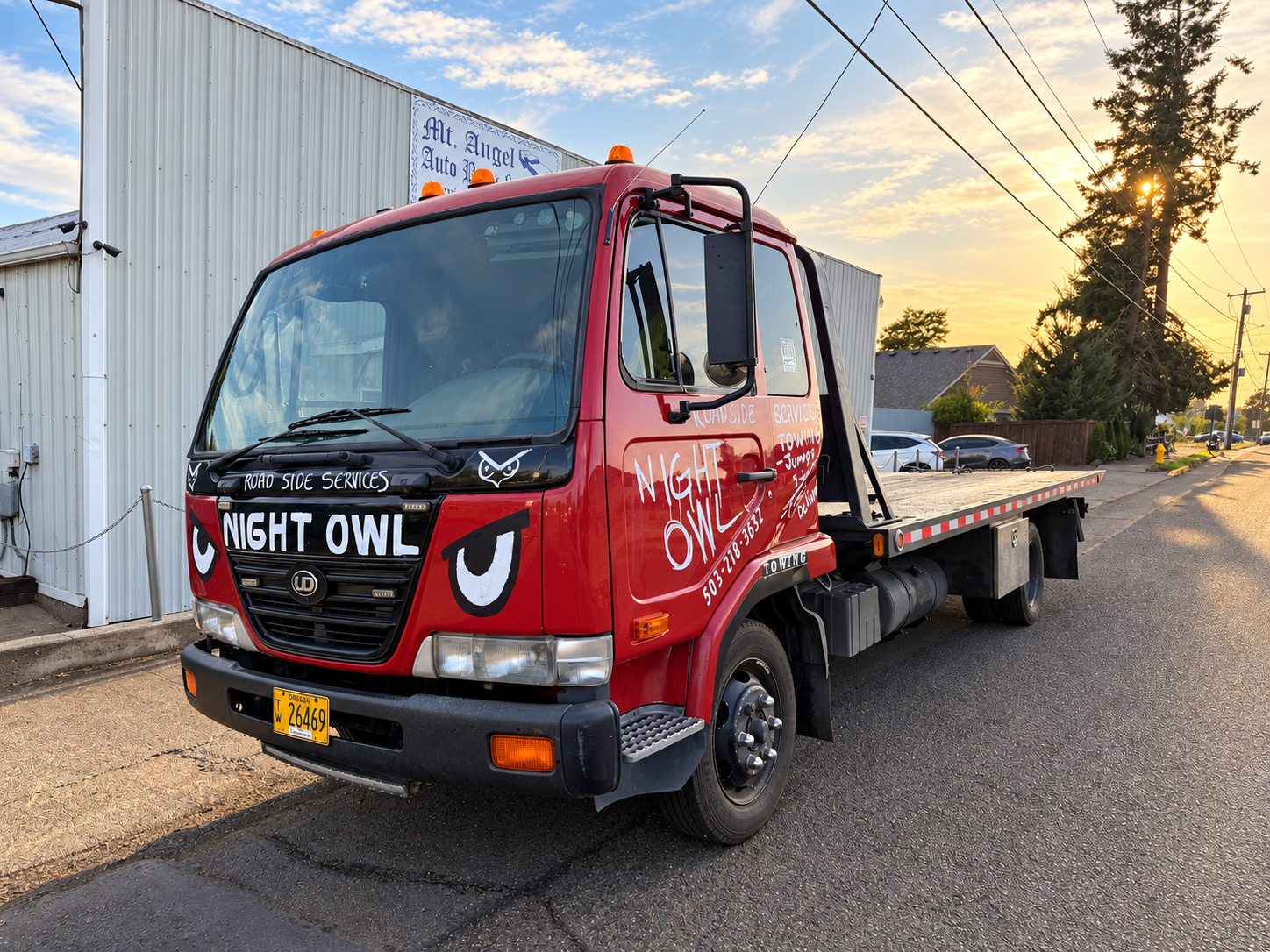Night Owl Roadside Services flatbed tow truck parked outside Mt. Angel Auto Body & Paint